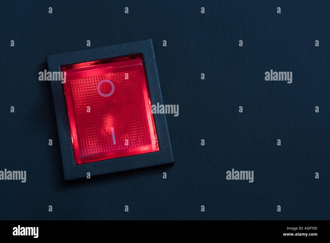Illuminated red electrical switch on black background potential