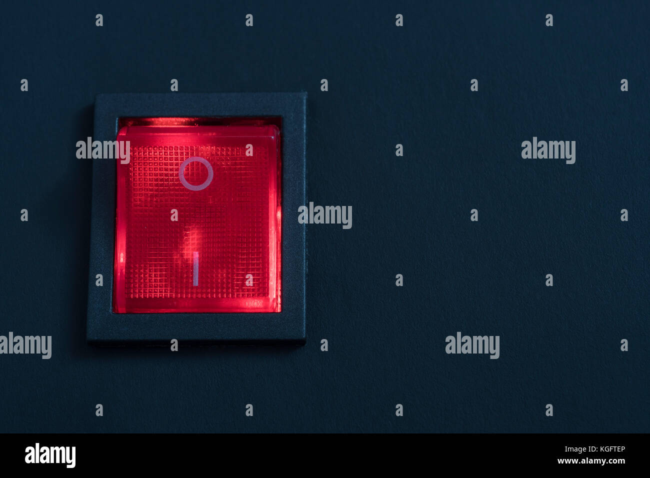 Illuminated red electrical switch on black background potential