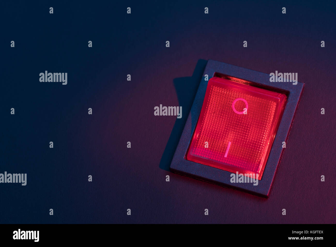 Illuminated red electrical switch on black background potential