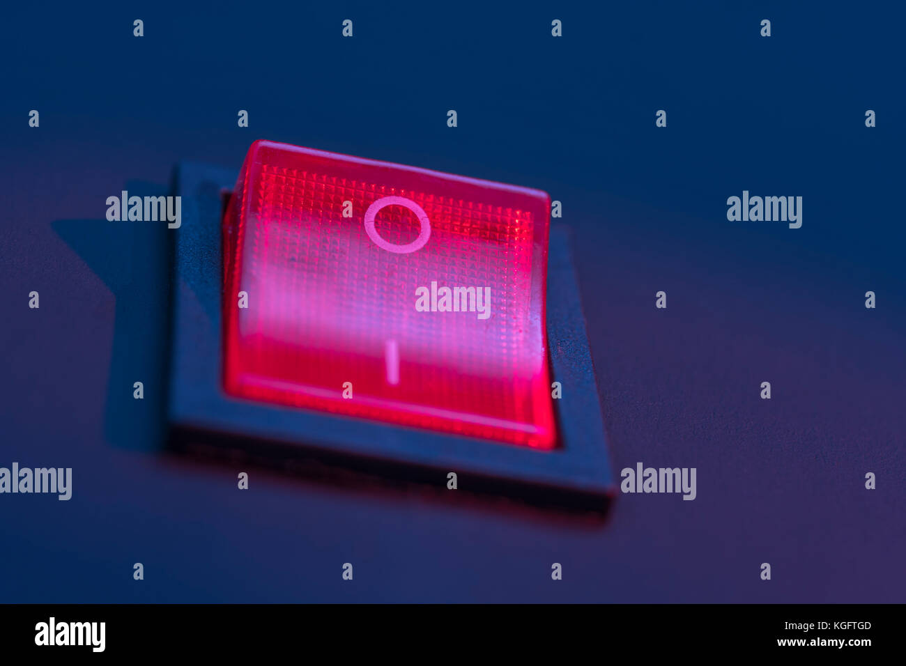 Illuminated red electrical switch on black background potential