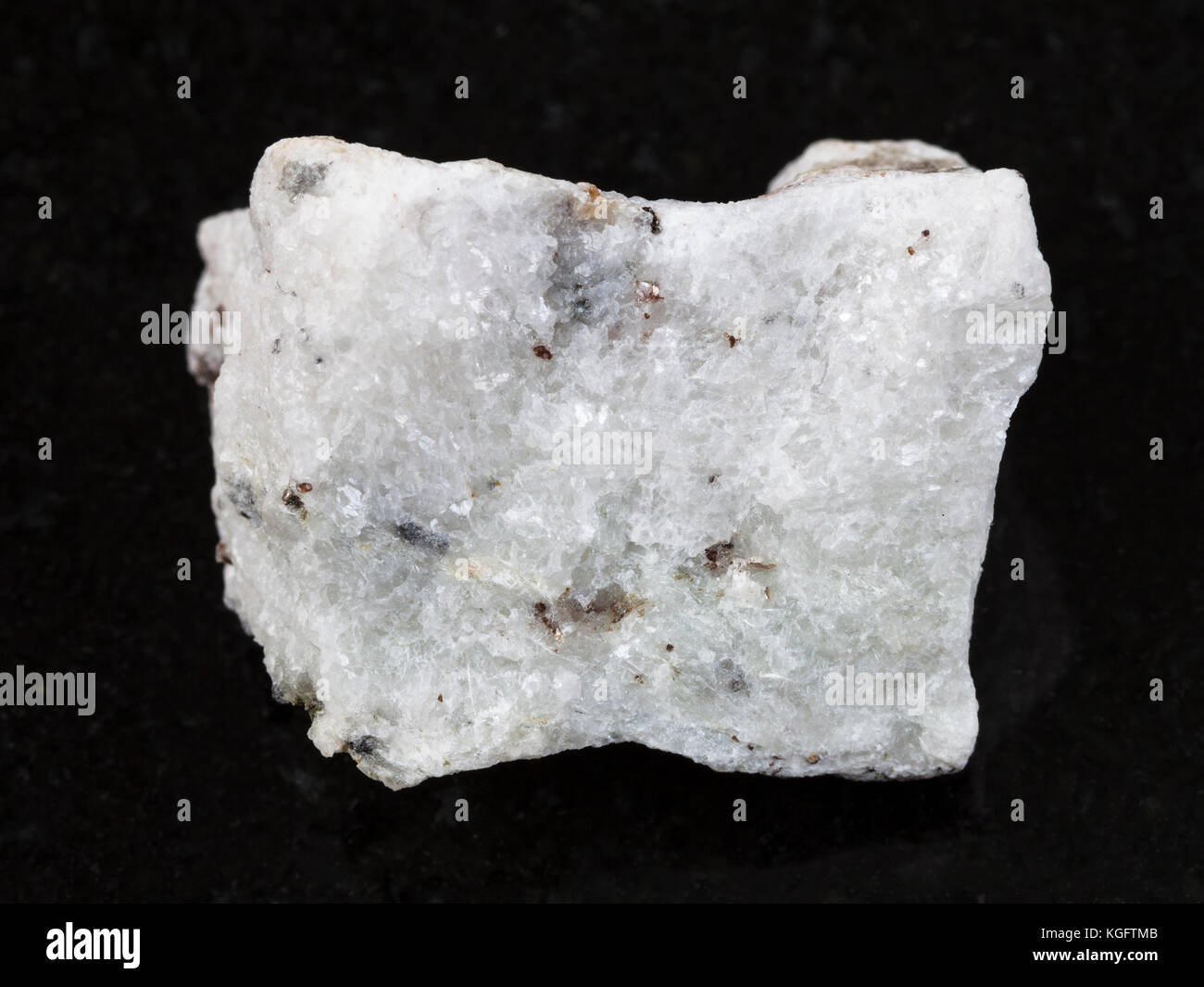 macro shooting of natural mineral rock specimen - rough carbonatite stone on dark granite background Stock Photo