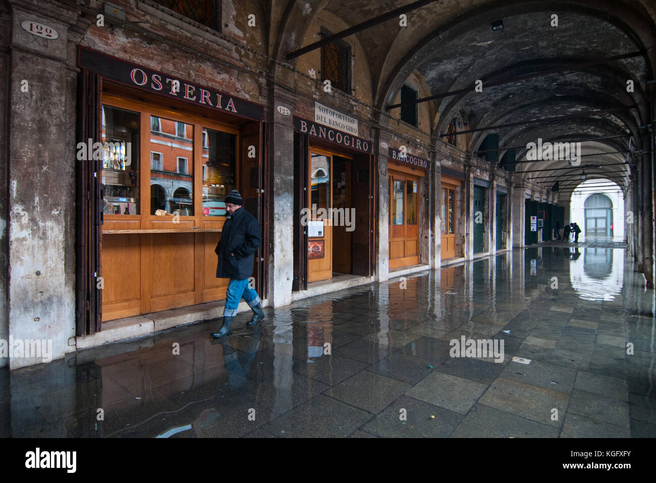 Venice, Italy. 07th November, 2017.  A man walks in the high water under a portico during an high tide on November 7, 2017 in Venice, Italy. Stock Photo