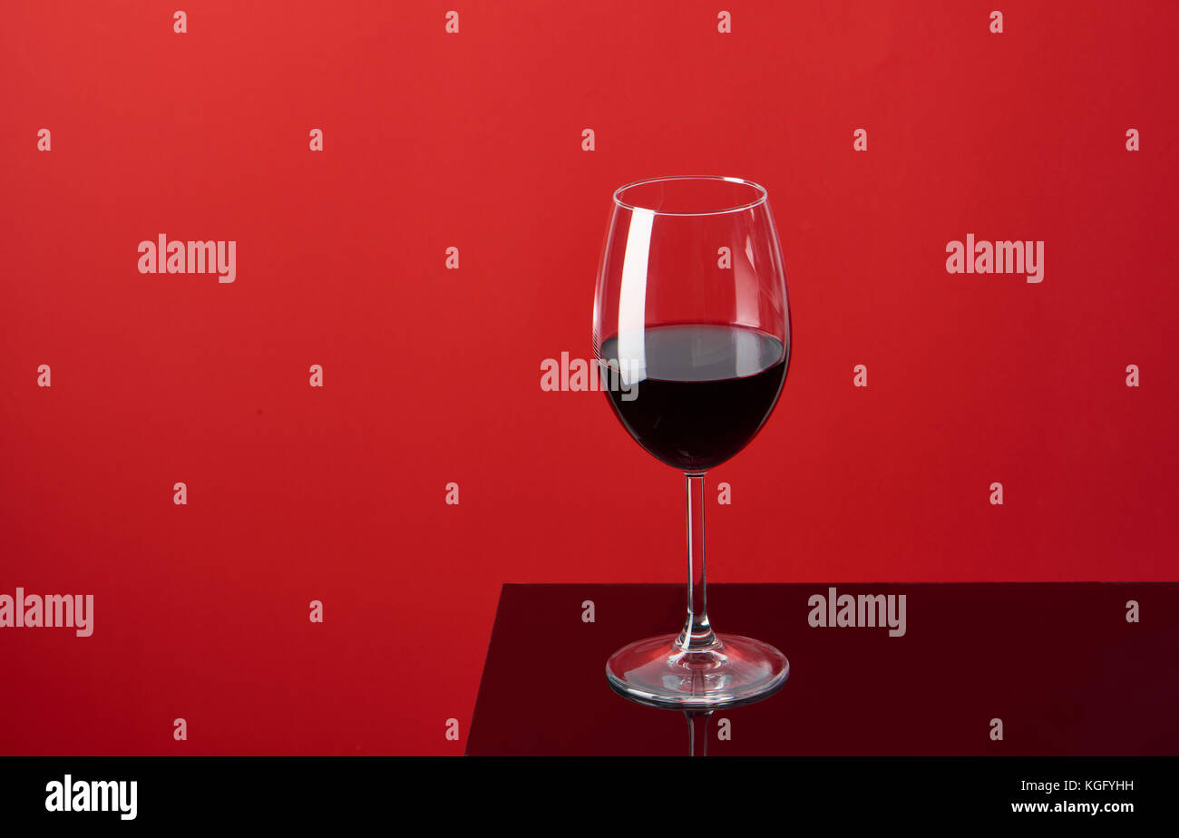 Glass of red wine on red background Stock Photo