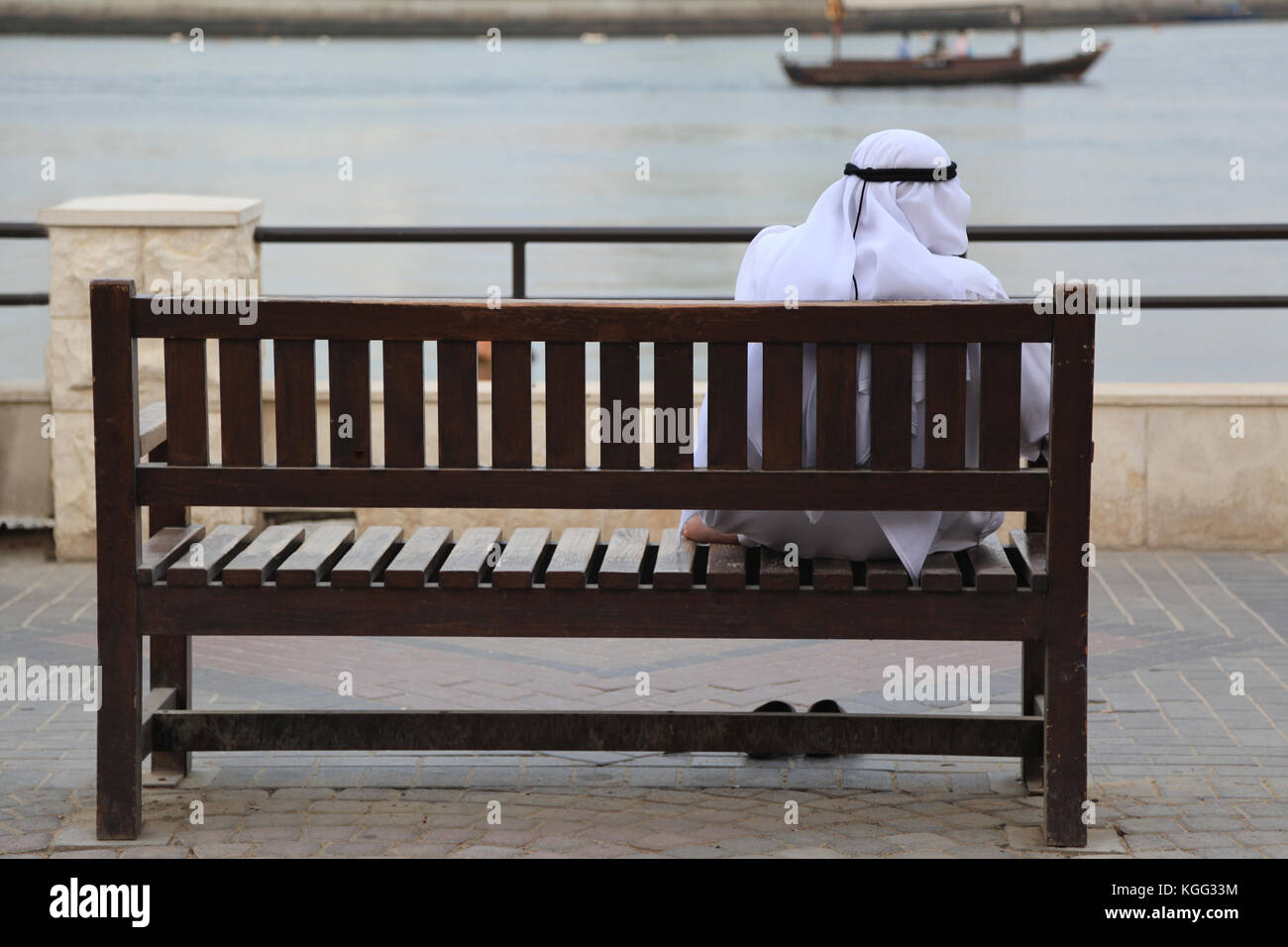 Adult Arab Man Wearing Traditional Dishdasha Sitting On A Bench In