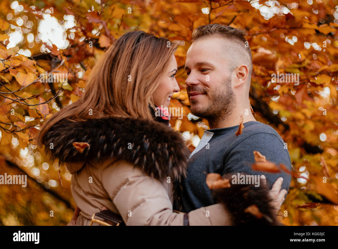 Portrait of a beautiful young couple in sunny forest in autumn colors ...
