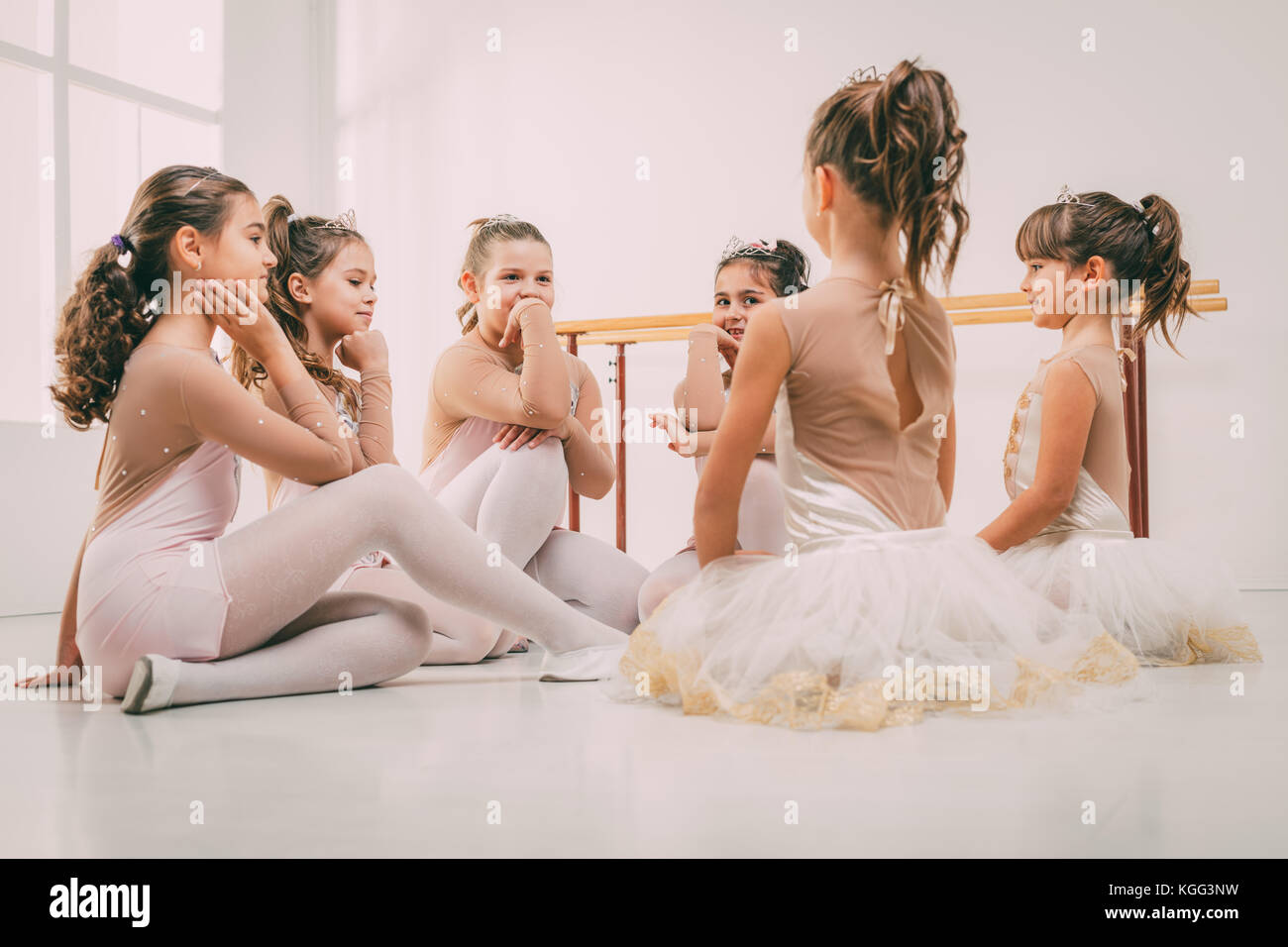 Group of a little girls in dresses taking a break from ballet class