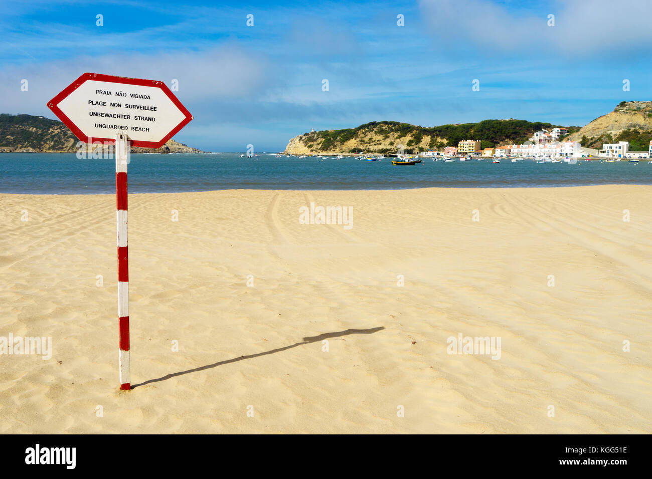 Unguarded Beach sign in four languages on red and white post on the beach in São Martinho do Porto, Silver Coast, Portugal, October 2017 Stock Photo