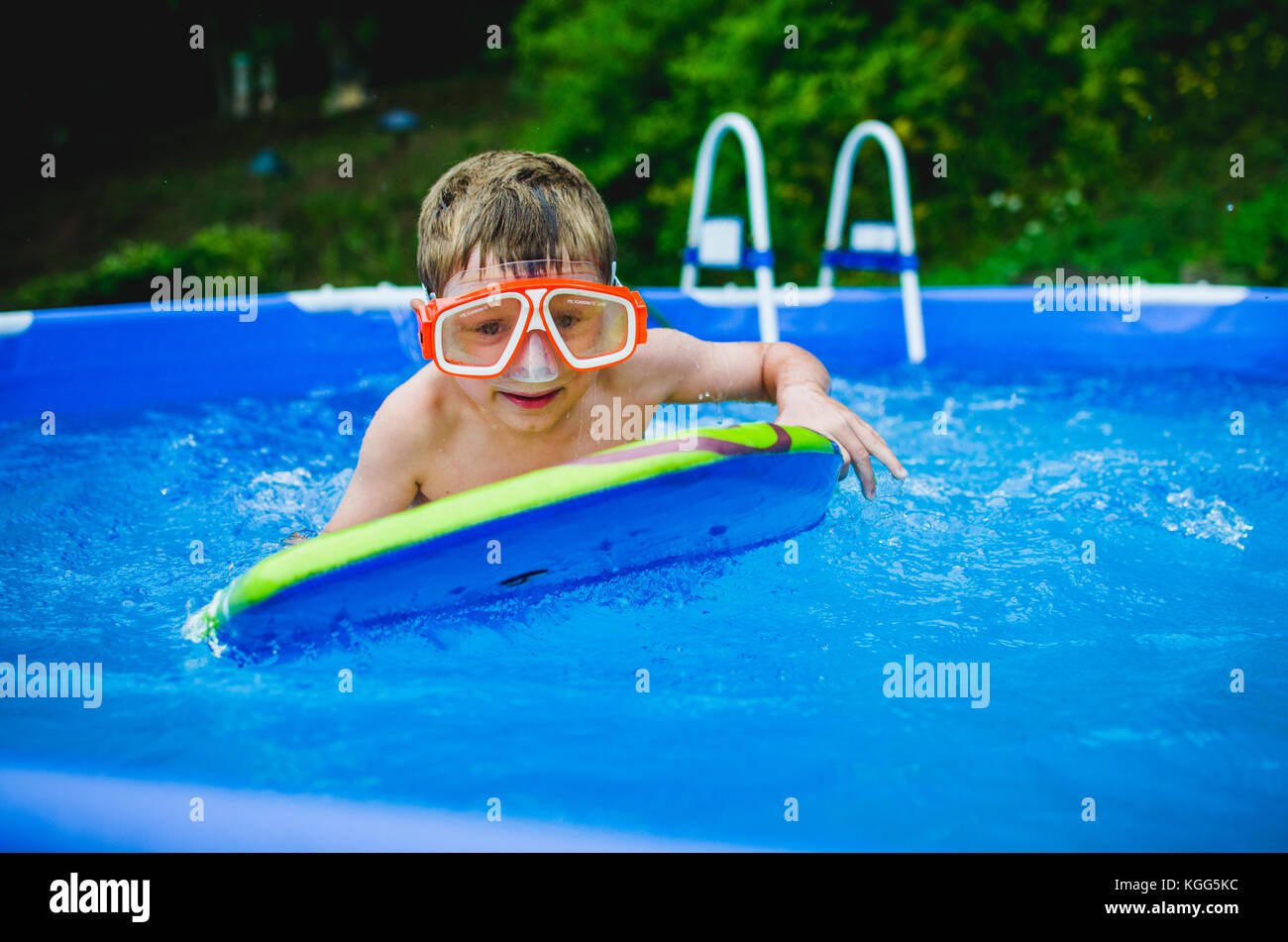 8-9 year old playing on a boogie board in a pool in summer. Stock Photo