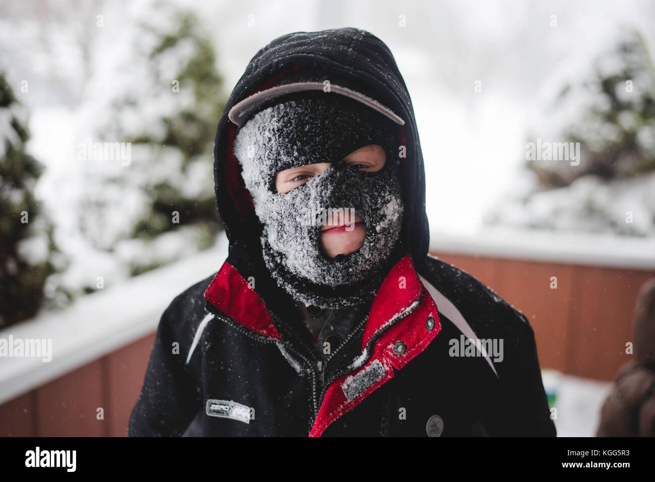 Child wearing a ski mask covered in snow Stock Photo