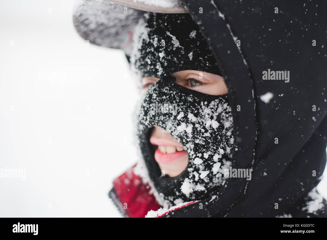 Child wearing a ski mask covered in snow Stock Photo