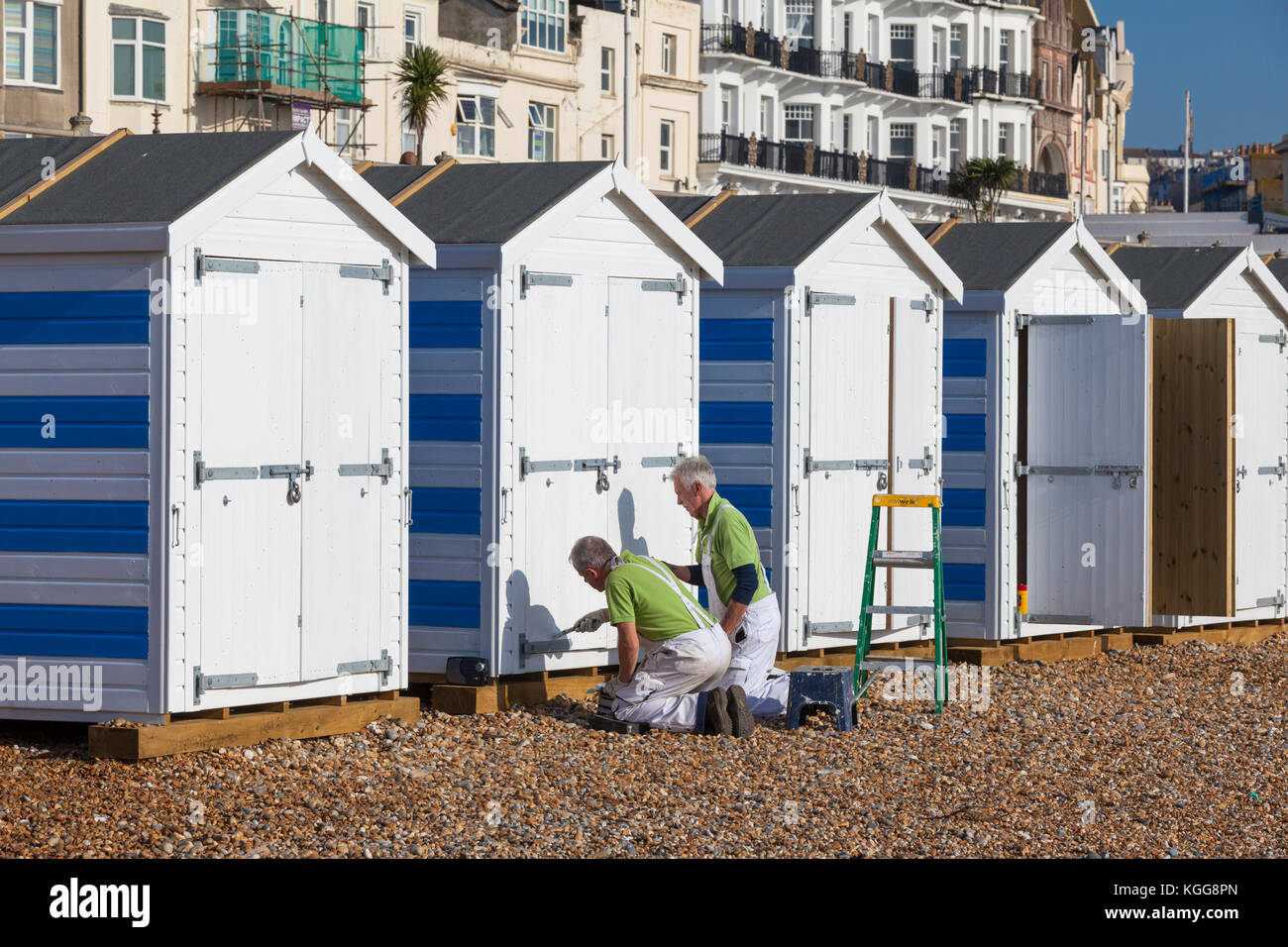 Two men painting beach huts on the Hastings seafront, East Sussex Stock Photo