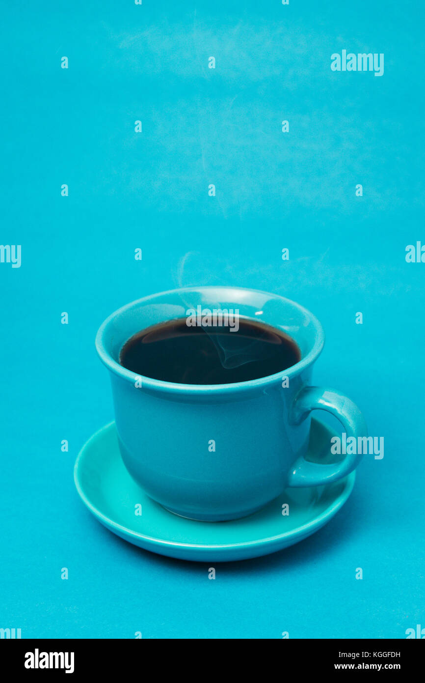 Blue mug with steaming hot coffee. Soft smoke. Blue background. Vertical photo Stock Photo