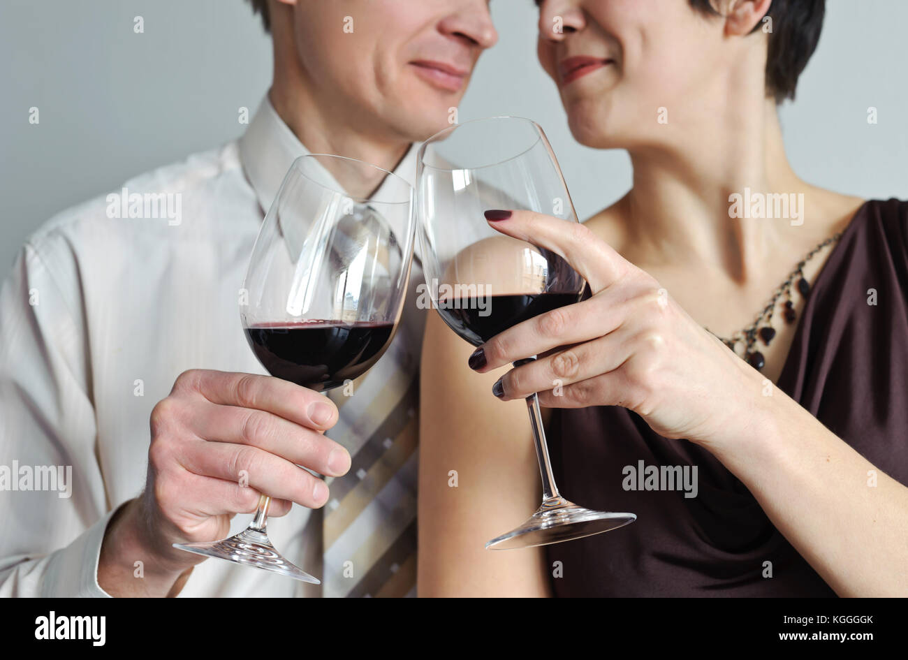 Close-up. Woman holding a glass of red wine leaning to the man Stock Photo