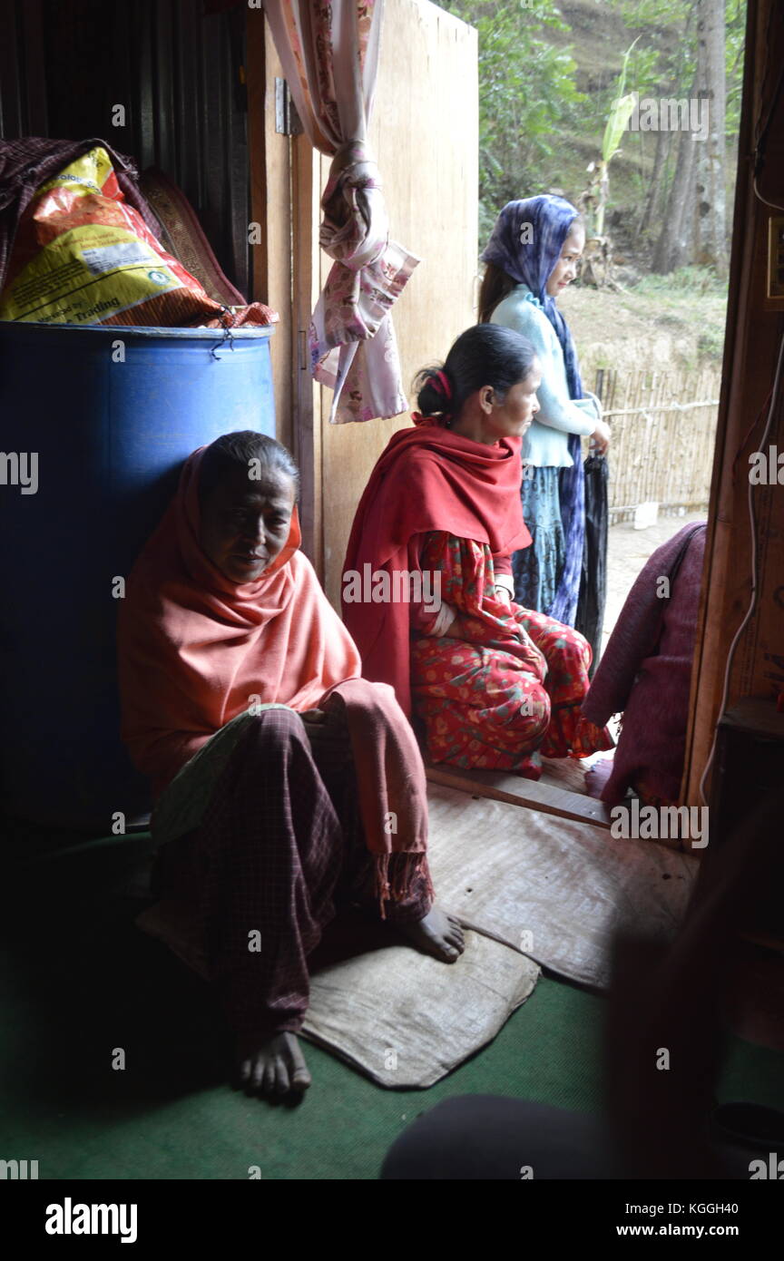 Four nepalese women are waiting inside of their house for the rain to stop. Traditional clothing, Halwar Kameez with scarfs. Village, Panauti, Nepal. Stock Photo