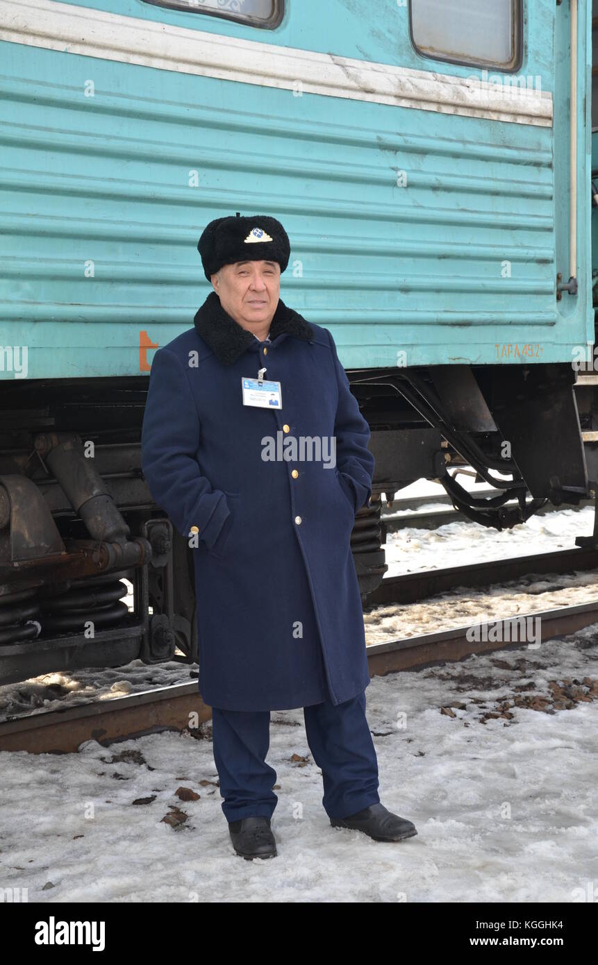 Kazakh train conductor, prodvodnik, with golden tooth and ushanka fur hat. Train in Kazakhstan during winter. Ice cold. -13 fahrenheit, -25 celcius. Stock Photo
