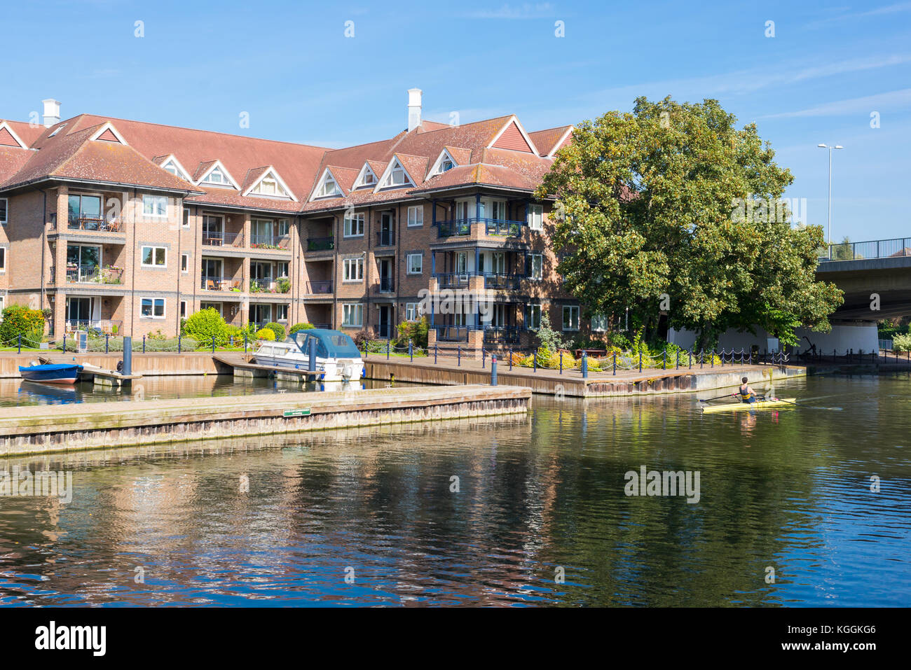 Big waterfront residential complex on the river Cam and student rowing on a single scull in Cambridge England, Uk Stock Photo