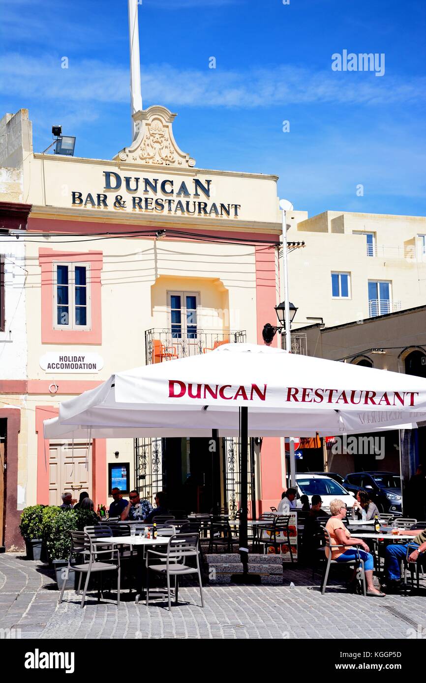 Tourists relaxing at a pavement cafe, Marsaxlokk, Malta, Europe. Stock Photo