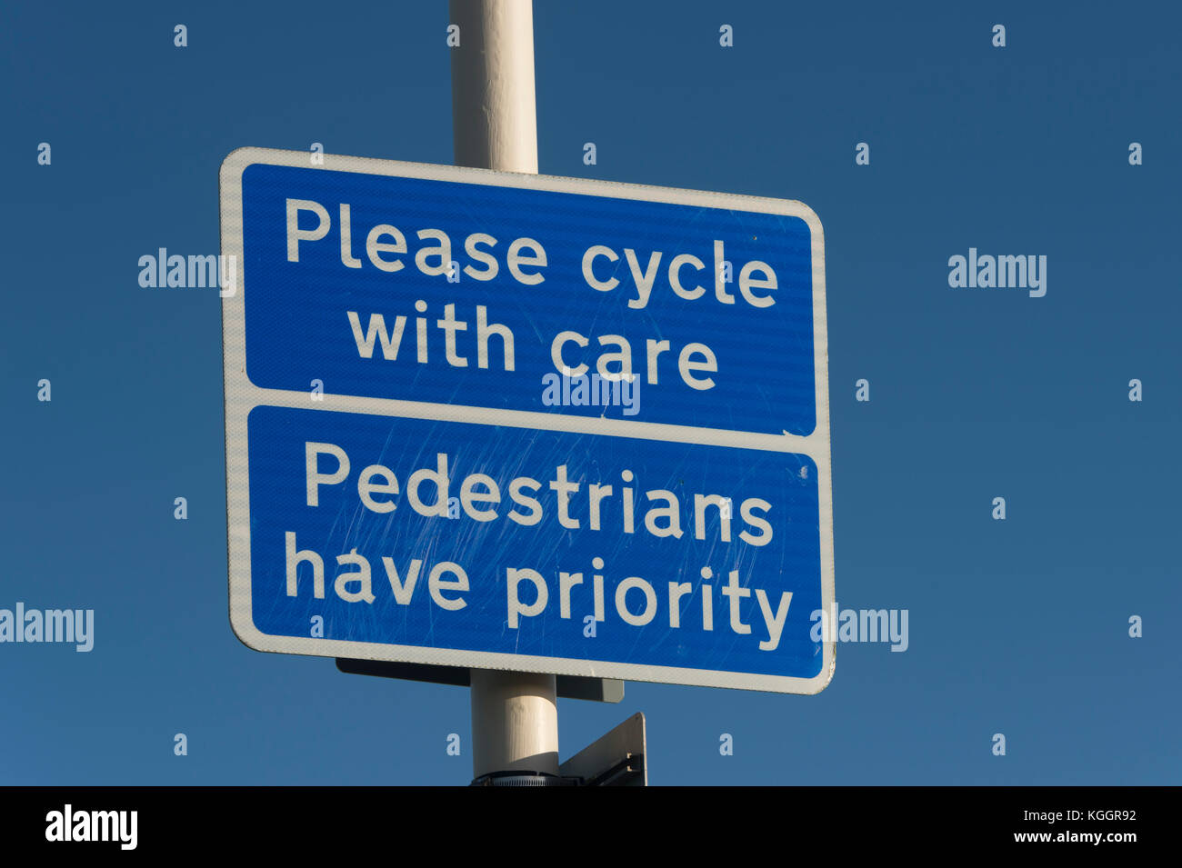 blue road sign, 'Please cycle with care', 'Pedestrians have priority' . Stock Photo