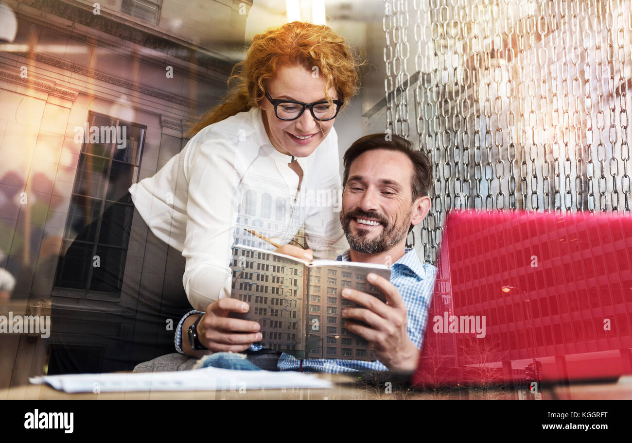 Cheerful man showing his notes to his female colleague Stock Photo