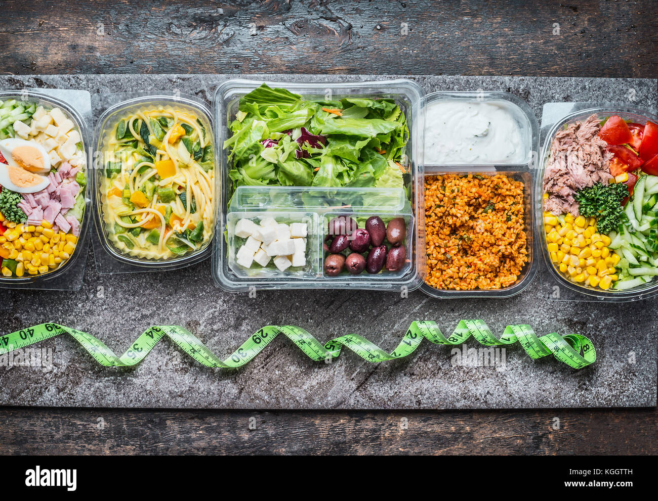 Various Healthy lunch boxes in plastic package and green measuring tape