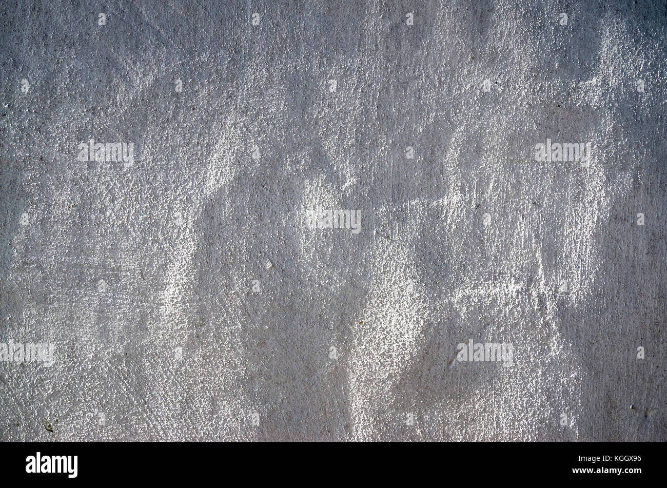 Abstract background formed by sunlight glancing across a rough cast plaster coat on an old barn wall Stock Photo