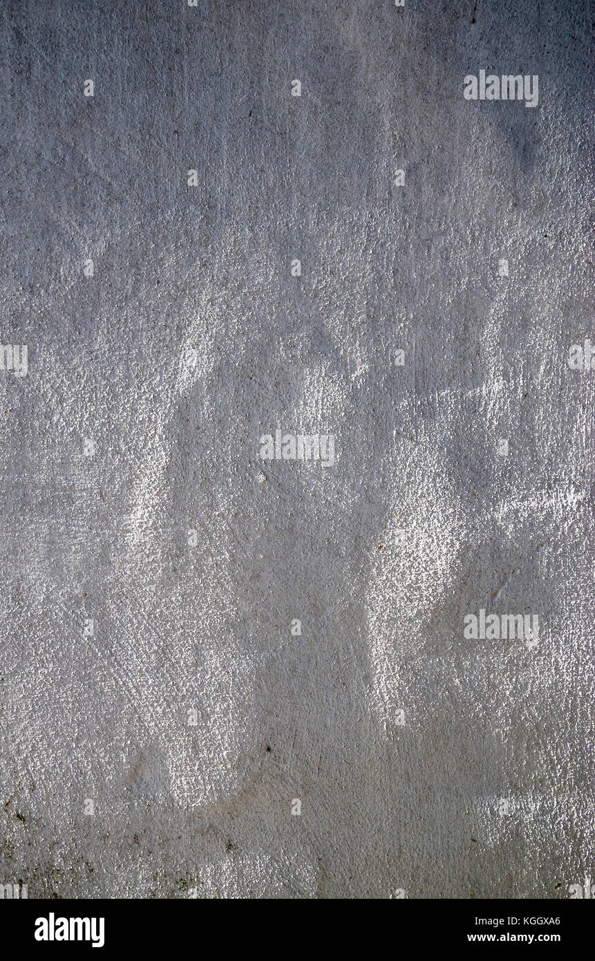 Abstract background formed by sunlight glancing across a rough cast plaster coat on an old barn wall Stock Photo