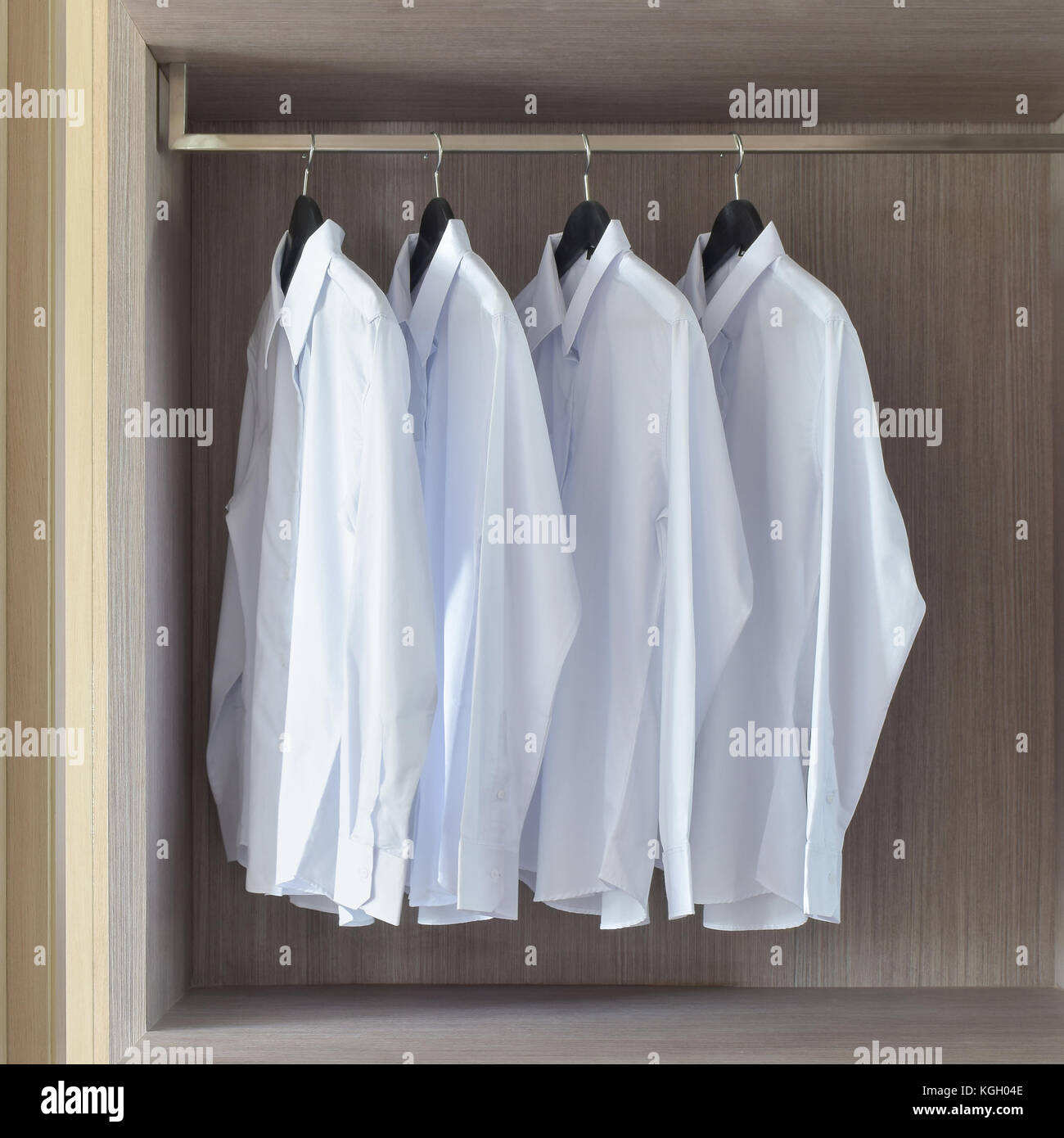 Classic white shirts in warm wooden wardrobe Stock Photo