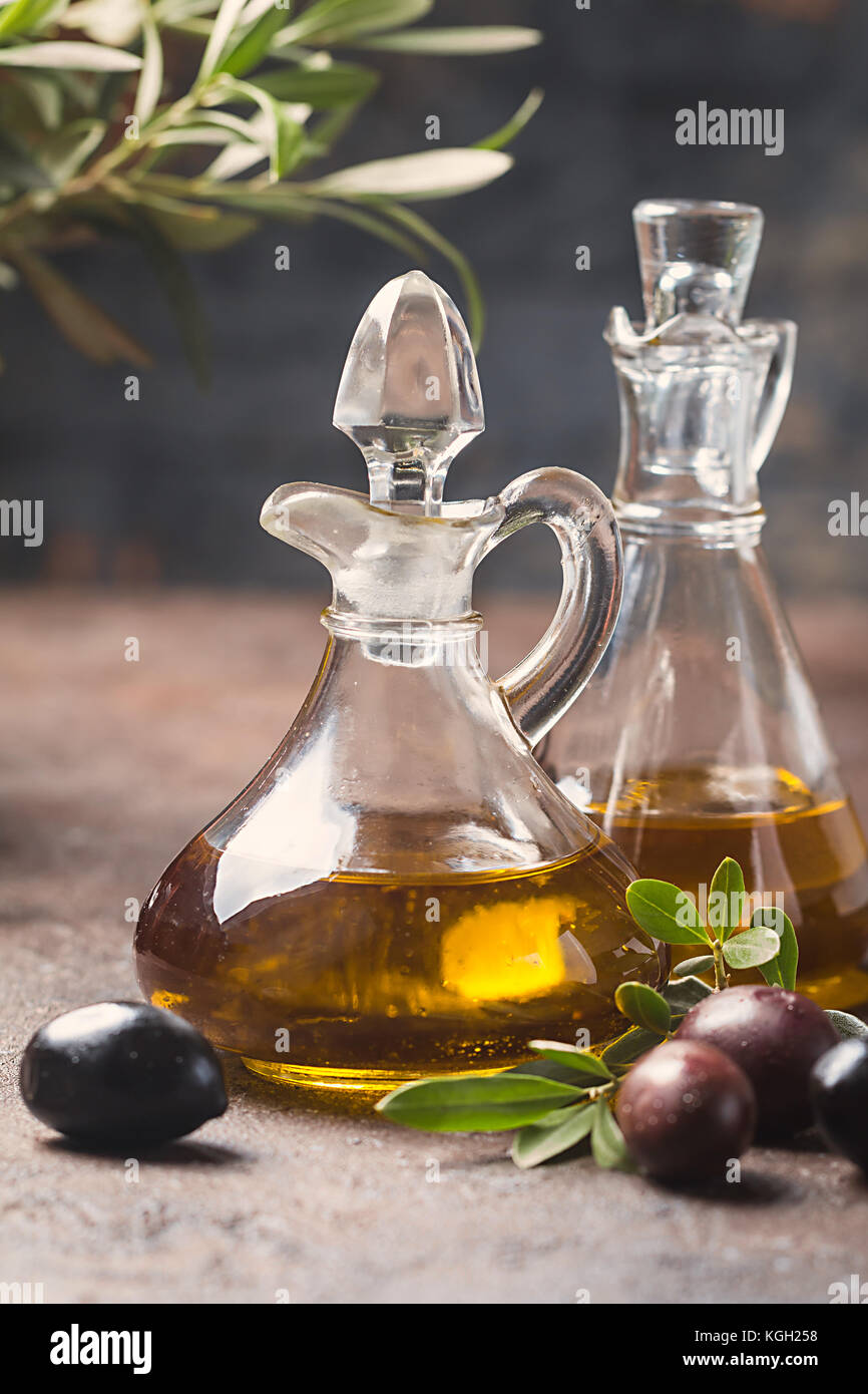 Olive oil in a glass bottle and olive branch on brown stone table Stock ...