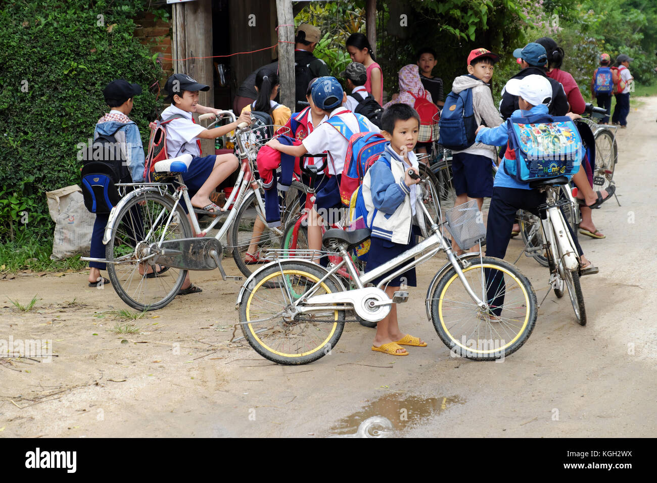 BINH DINH, VIET NAM, group of Asian children stand together after school on bicycle, at Vietnamese countryside, pupil cycling to go to school Stock Photo