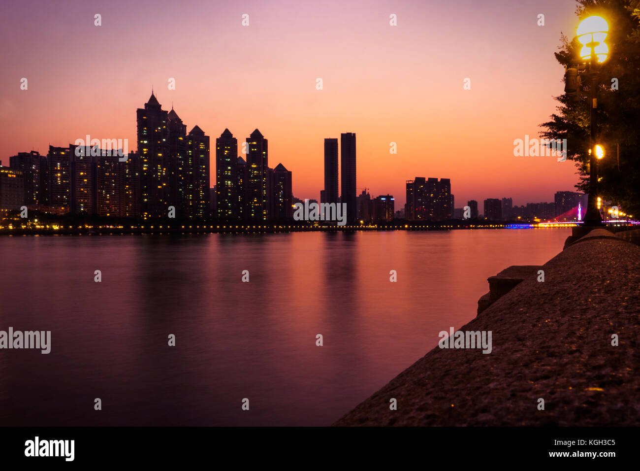 Dusk falls over the Pearl River and the City of Guangzhou, capital of Guangdong province. Luxury apartments are light up in the background. Stock Photo