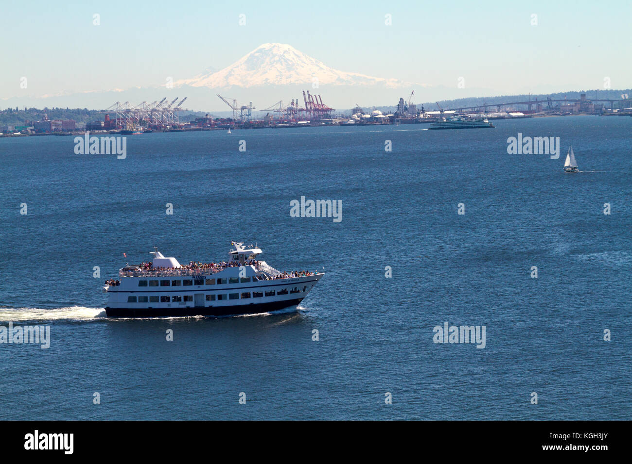 A tour-boat crowded with sightseers in Seattle with Mt. Rainier in the background.as seen from the deck of a cruise ship. Stock Photo