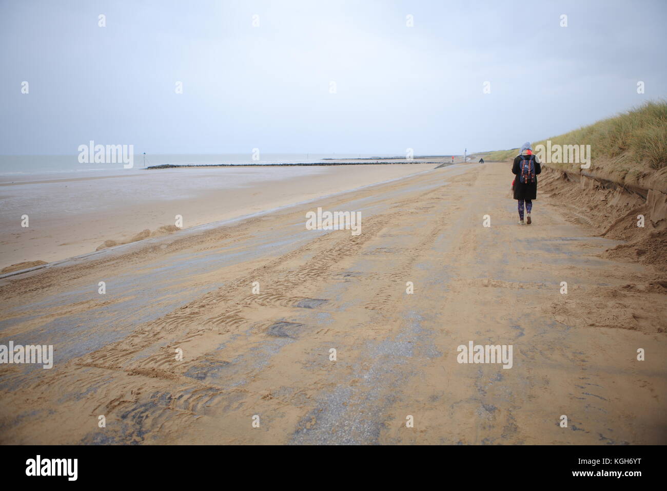 Woman walks along empty North Welsh beach, Prestatyn, November 2017 Stock Photo