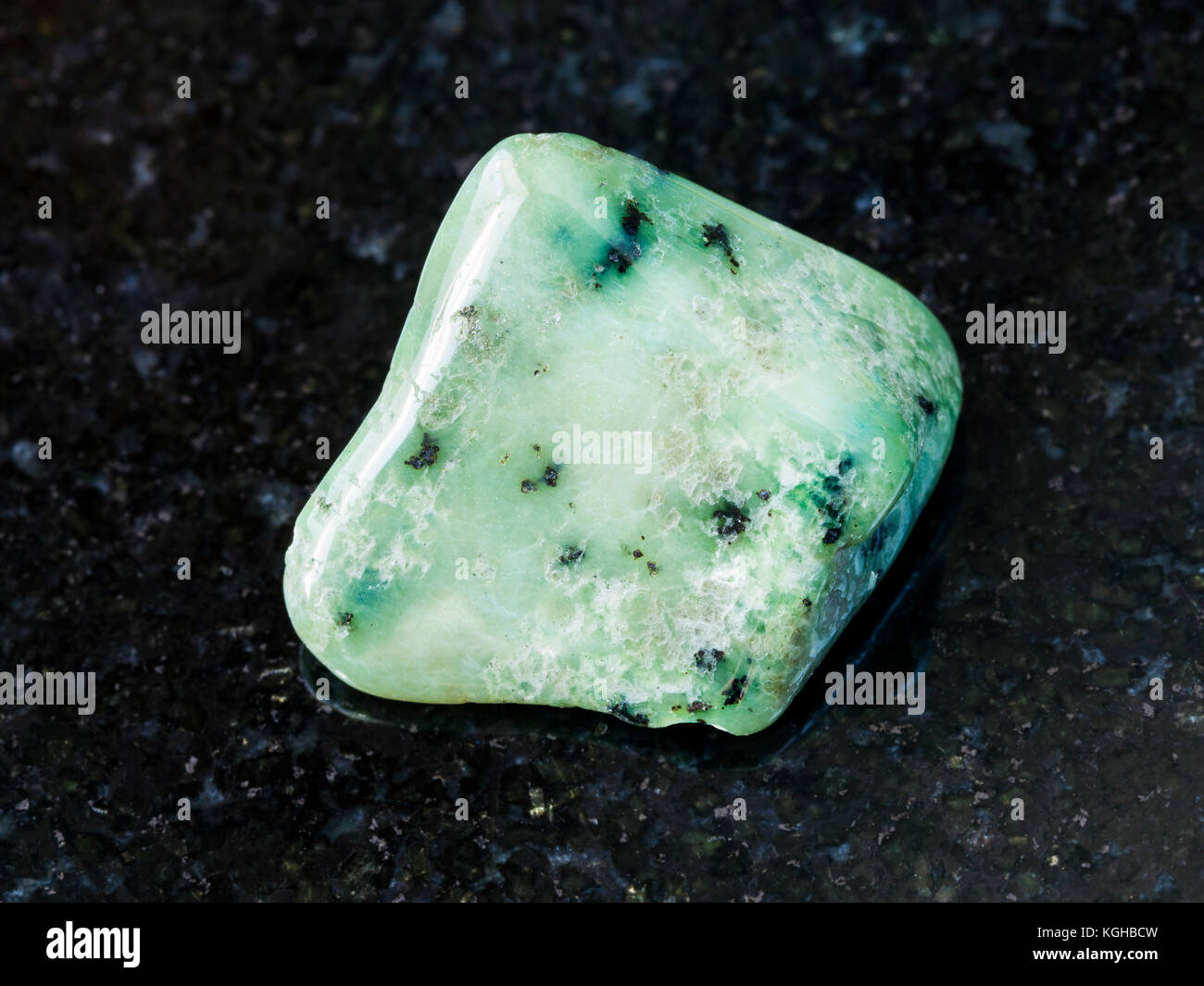 macro shooting of natural mineral rock specimen - polished green Grossular gemstone on dark granite background from South Africa Stock Photo