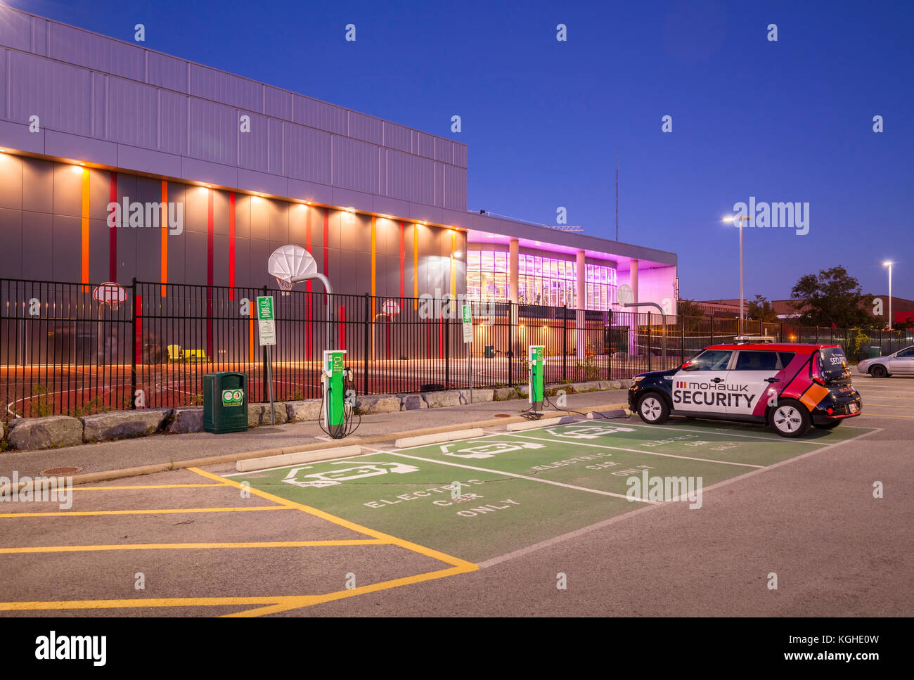 Electric vehicle parking spots, charging stations and an EV Mohawk Campus Security car in front of Mohawk College's Fennel Campus in Hamilton, Ontario Stock Photo