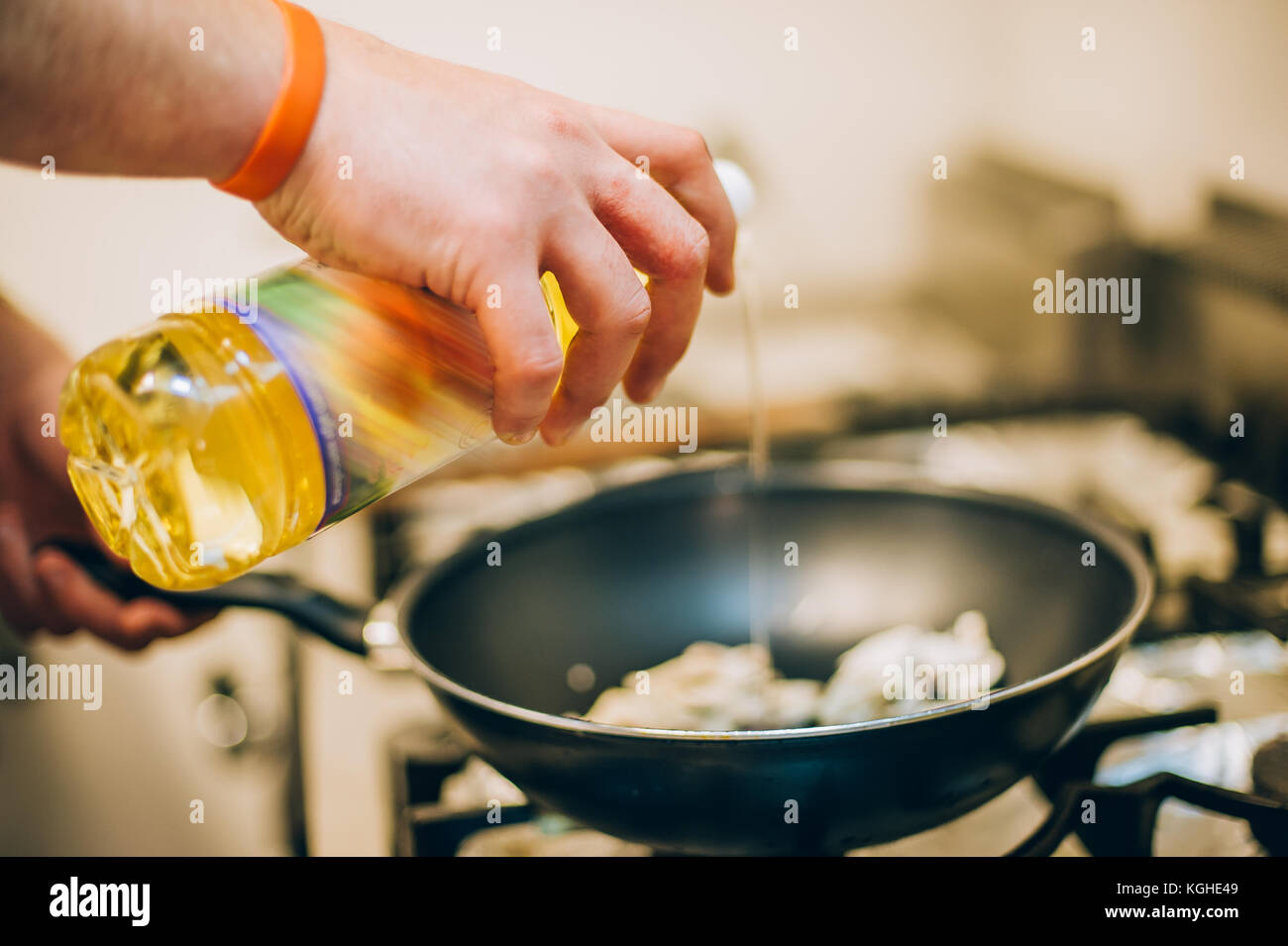 Chef cook pours oil into the frying pan in the kitchen in the restaurant Stock Photo