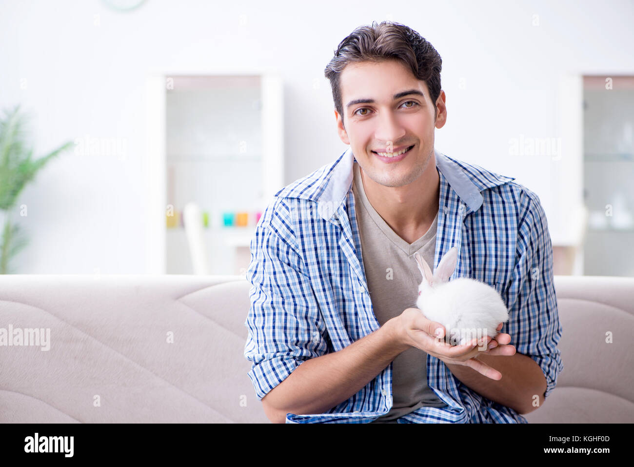 Young man playing with pet rabbit at home Stock Photo - Alamy