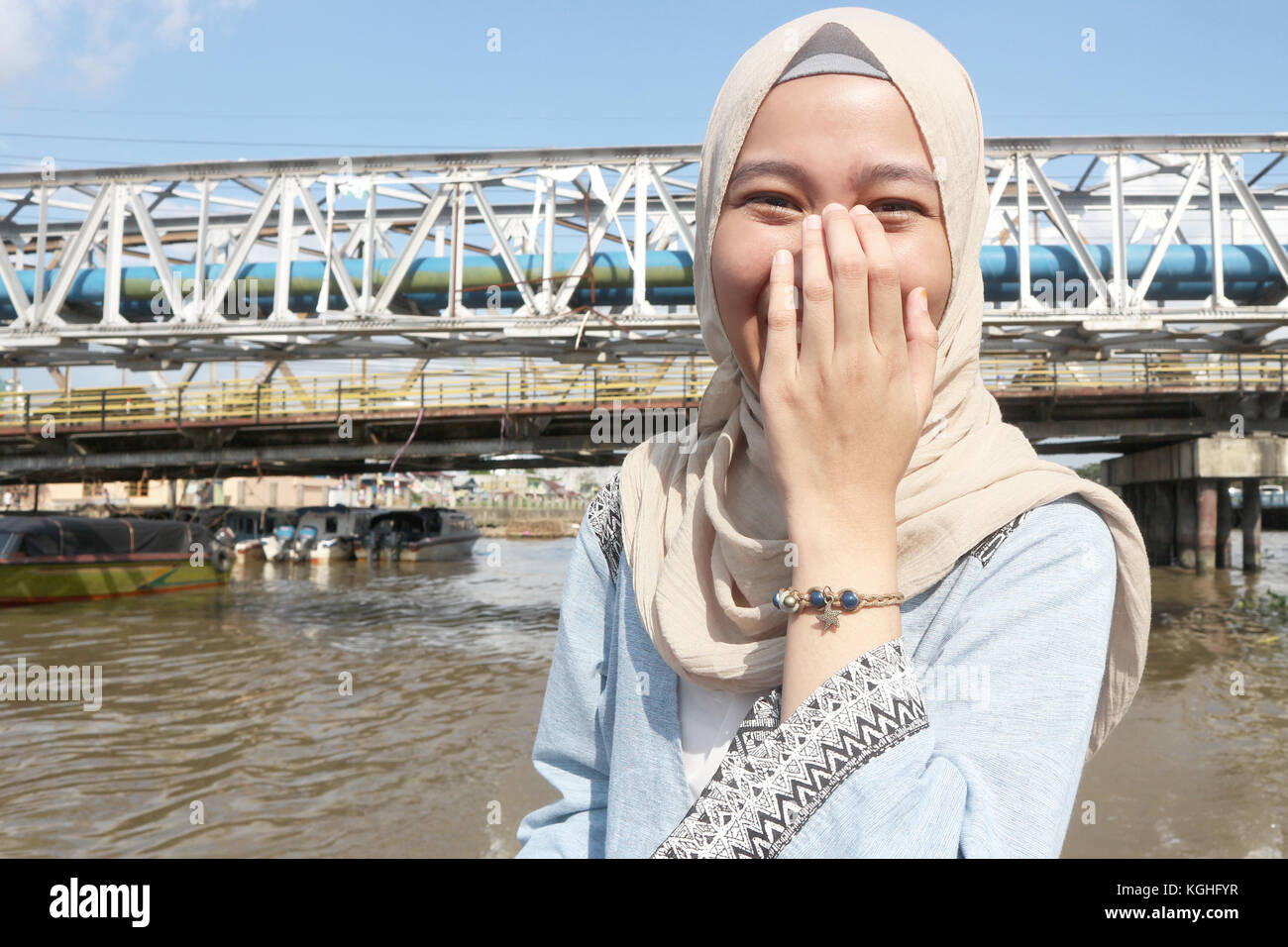 A happy and shy young Muslim women with hijab, at outdoor recreation weekend/ holiday activity at water side/ river Stock Photo