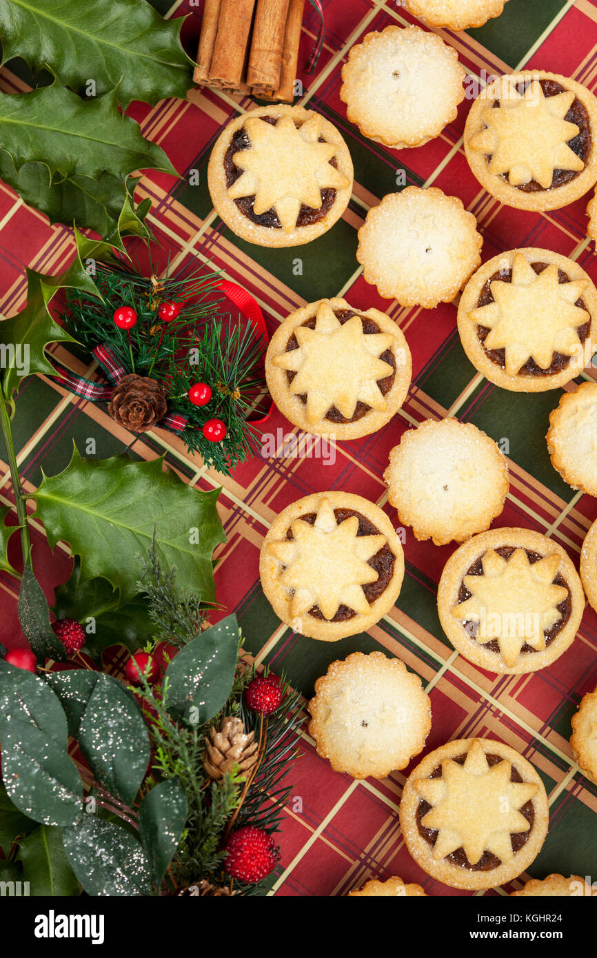 Christmas selection of mini frosted mince pies and holly leaves on a ...