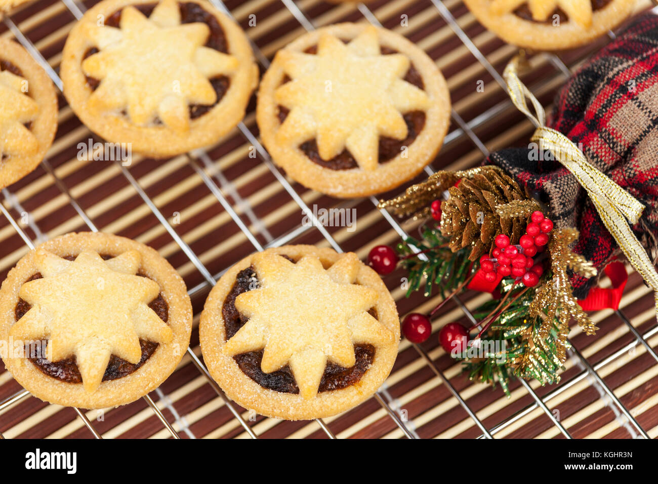 Freshly baked mini star topped mince pies on a cooling rack with a ...