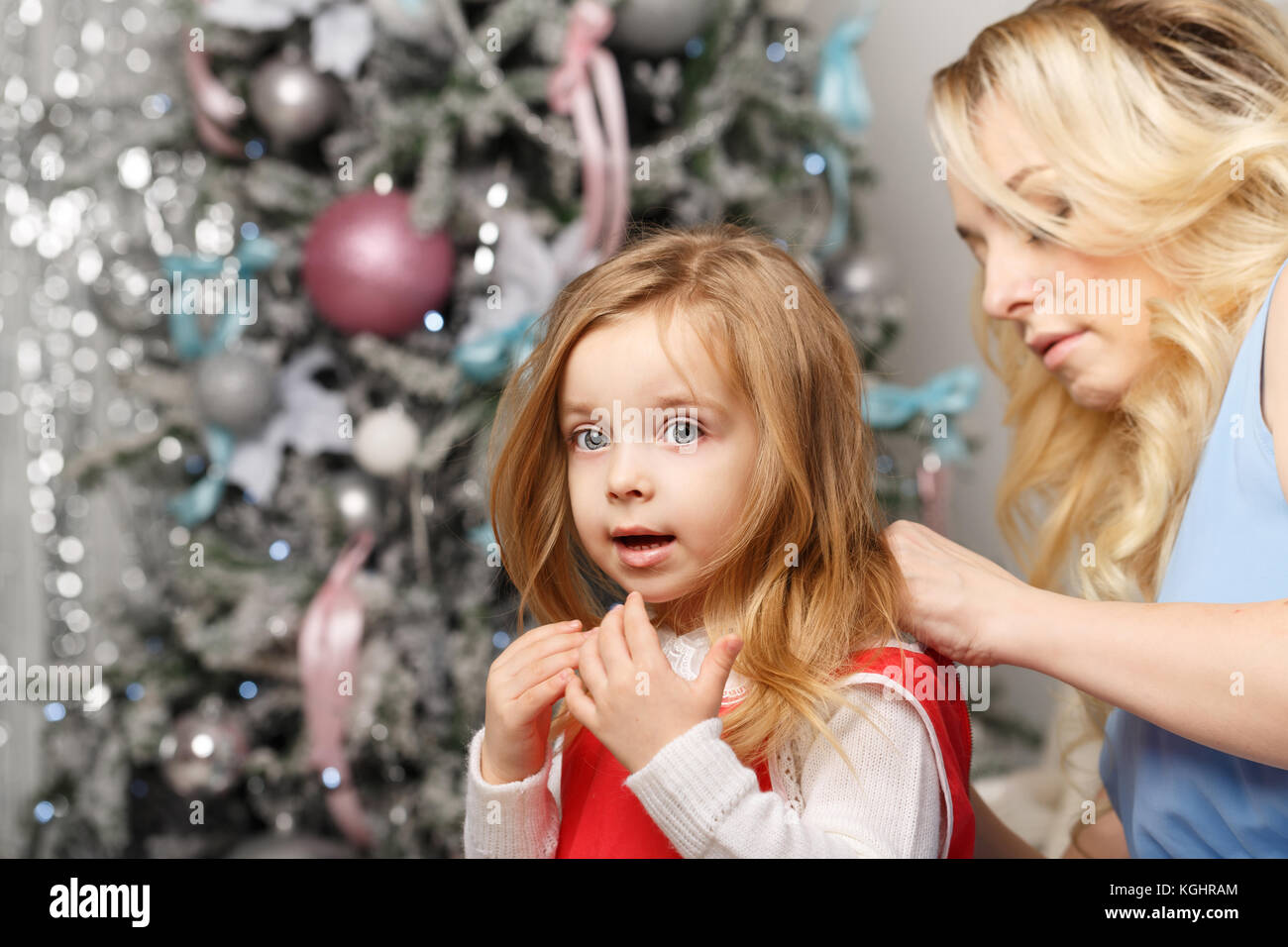 Family Christmas. Mother button up her daughter's dress. Preparation for the holiday. Stock Photo