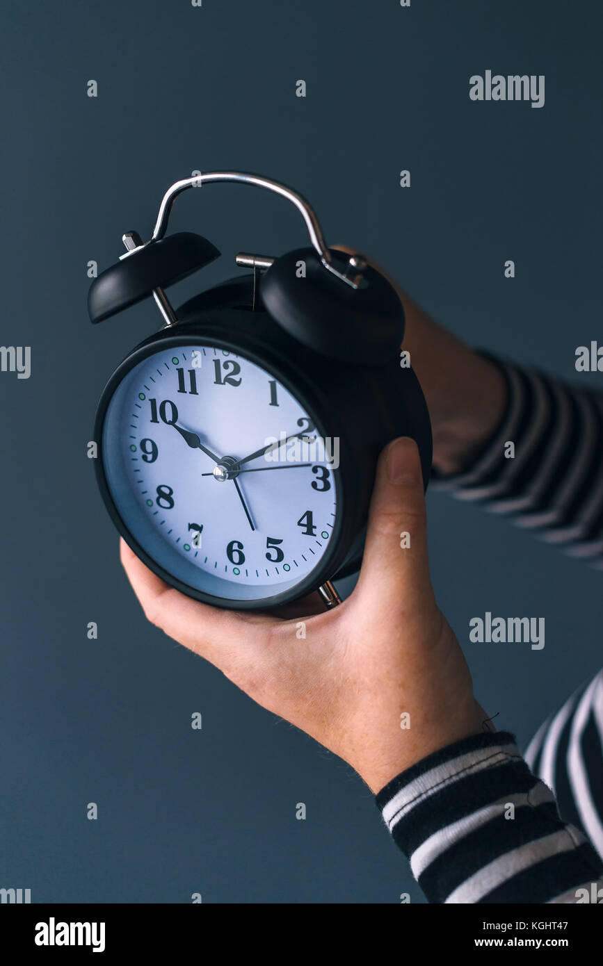 Woman winding retro alarm clock, concept of daylight saving time, selective focus Stock Photo
