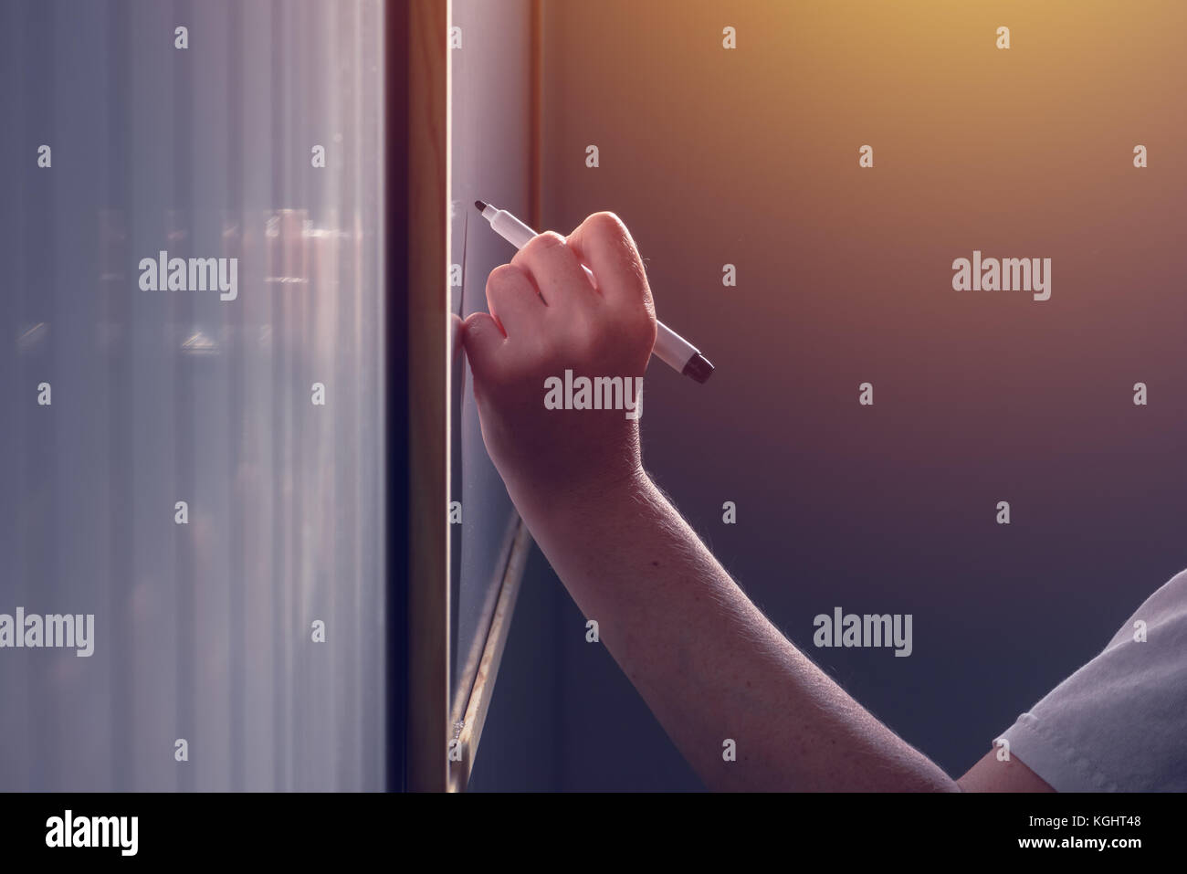 Lefthand female business person writing on office whiteboard with