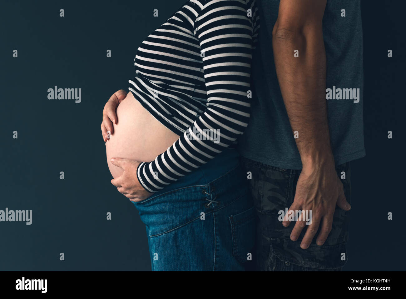 Soldier and his pregnant wife, couple expecting baby, low key Stock Photo