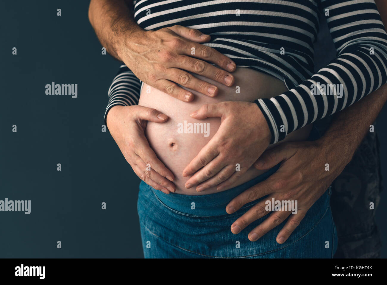Soldier hugging his pregnant wife, couple expecting baby, low key Stock Photo