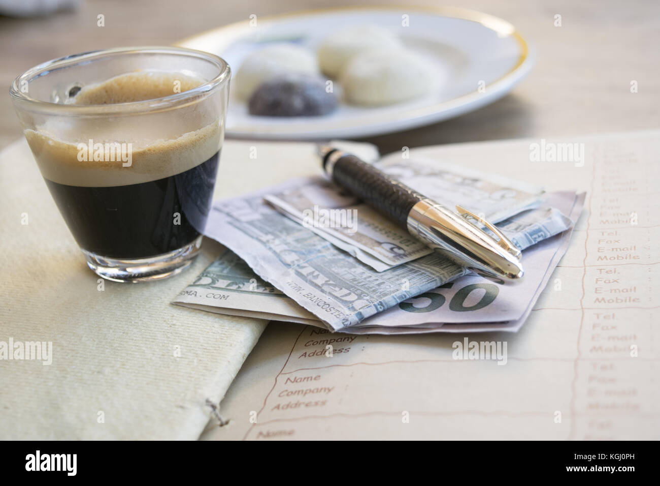 concept of business with an espresso coffee on a diary with money and a stylograph Stock Photo