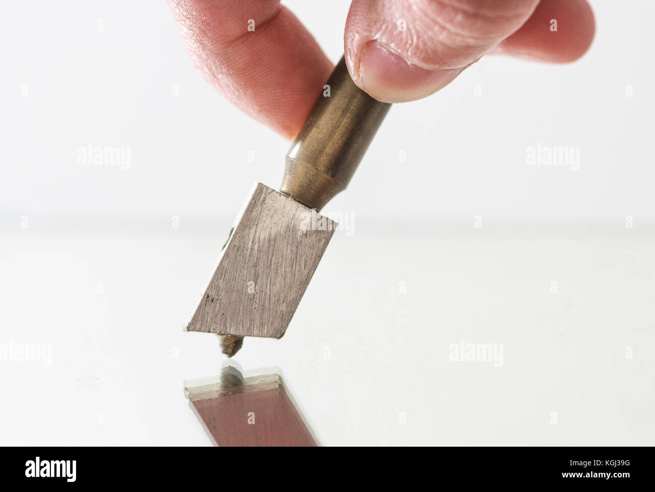 Hand holding and using Diamond tip glass cutter on a reflective mirror