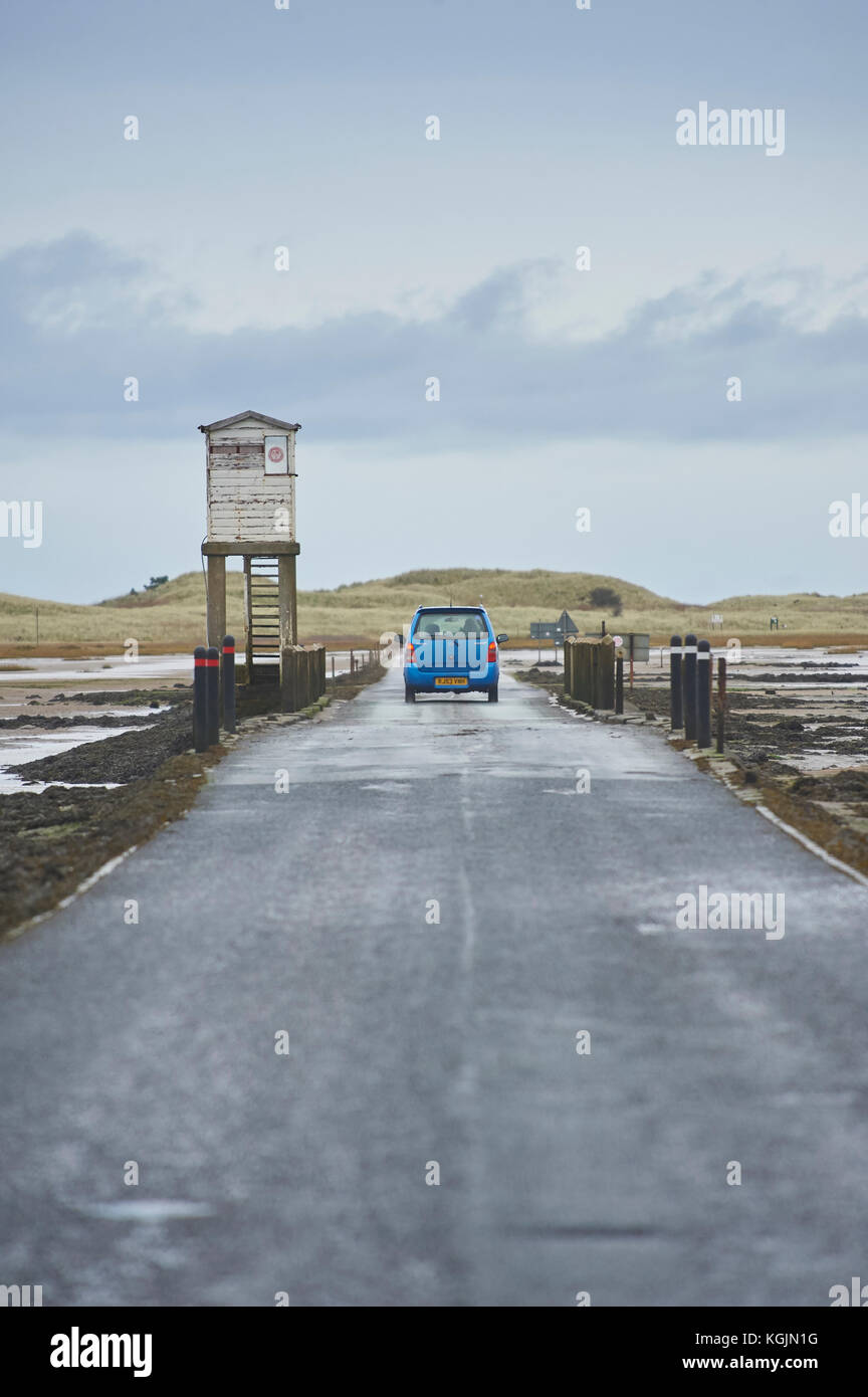 Car crossing tidal causeway to Lindisfarne (Holy Island) at low tide, Northumberland, UK Stock Photo
