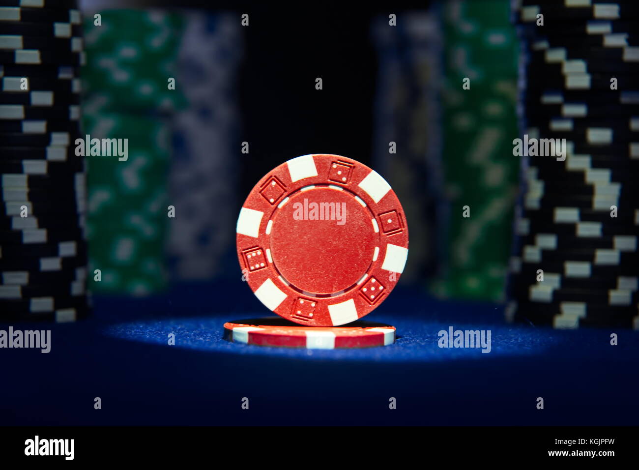 Closeup of poker chips on blue felt card table surface with spot light
