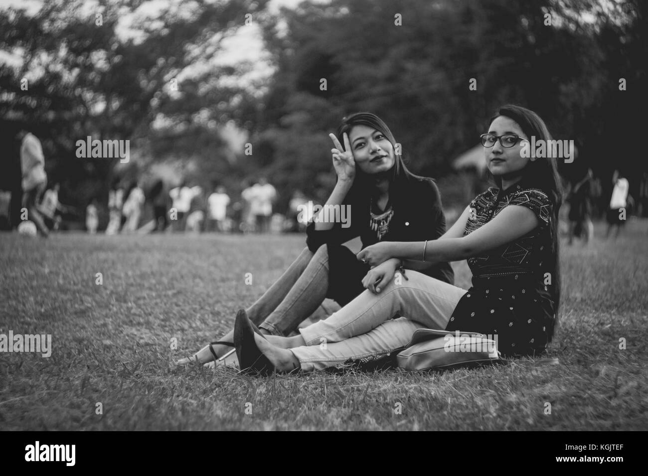 Two young girls having a talk while sitting down in the park of Marngar Lake. Stock Photo
