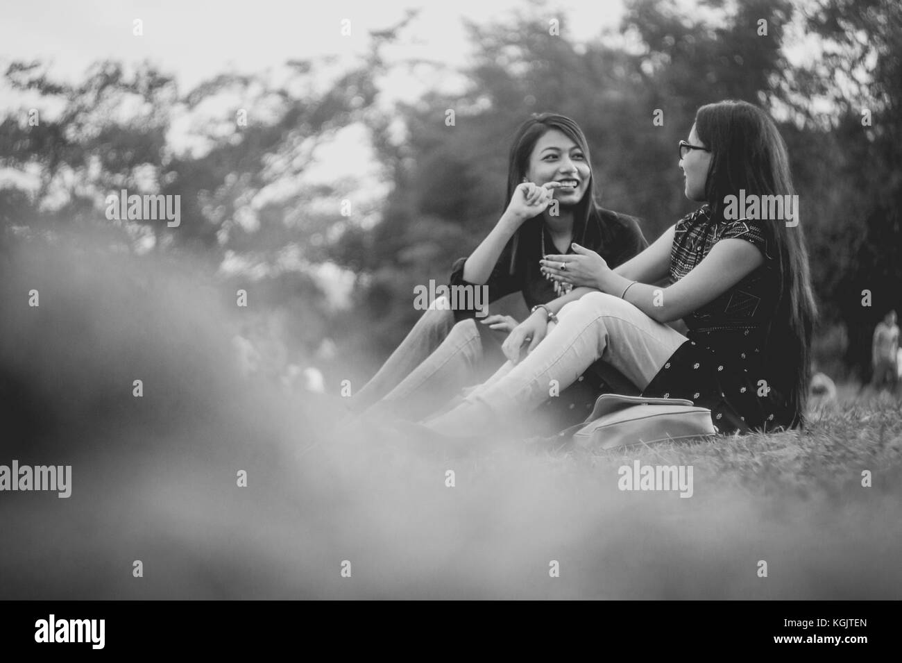 Two young girls having a talk while sitting down in the park of Marngar Lake. Stock Photo